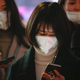 Women wearing face masks wait for the bu